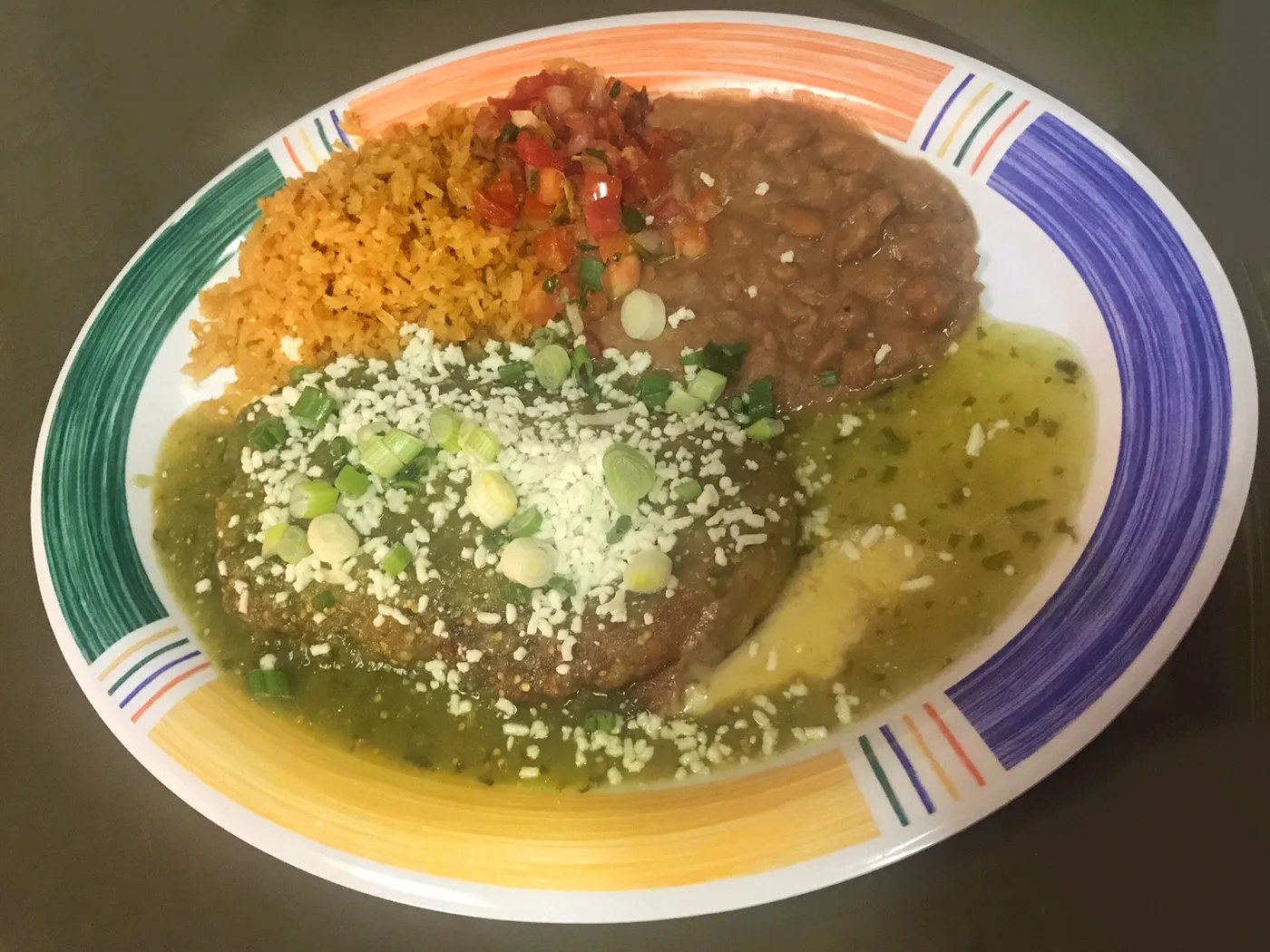 A chile relleno plate with salsa verde, rice and beans