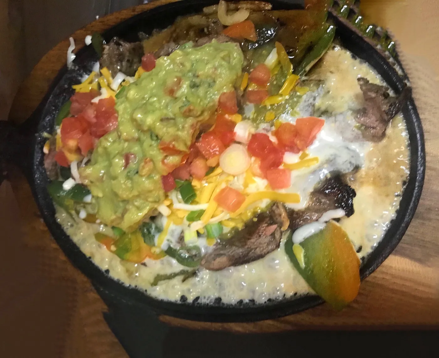A sizzling skillet topped with guacamole and pico de gallo