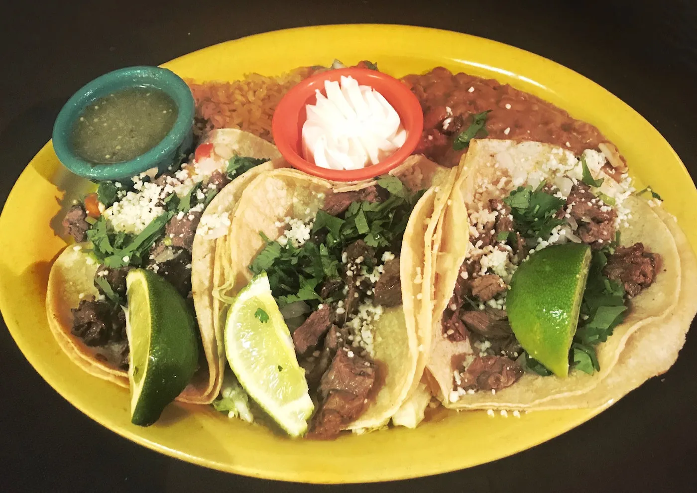 Three street tacos with lime and salsas